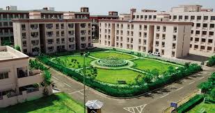 "Aerial view of the beautiful green central garden inside the People's University campus in Bhopal, surrounded by multistoried hostel or academic buildings."