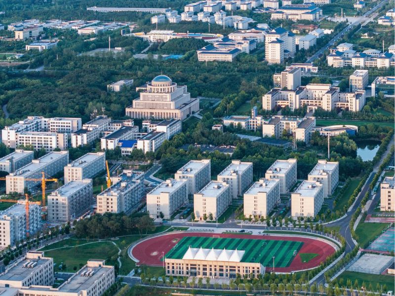 Modern university campus aerial view with academic buildings, hostels, and sports stadium.