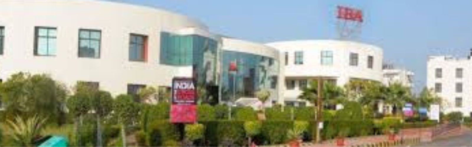 "Main building facade of Indus Business Academy (IBA) Bangalore campus with lush green gardens."