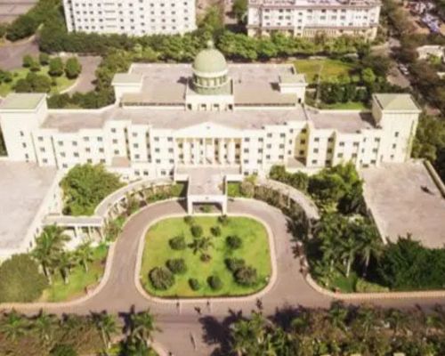 Alt Text: Aerial view of the Ajeenkya DY Patil University (ADYPU) Pune campus building, featuring classic white architecture with a central dome and lush green landscaping.